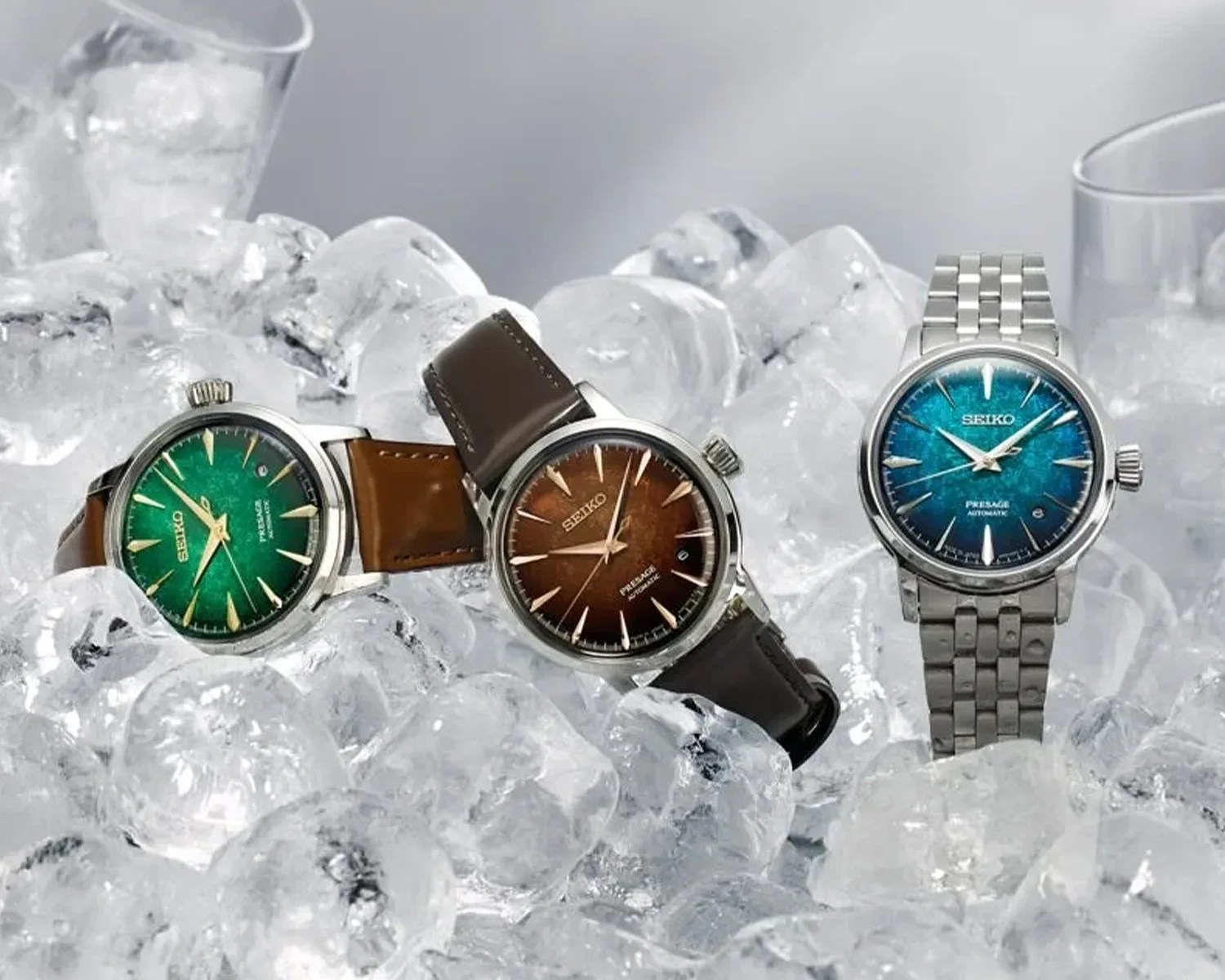 Three Seiko Presage automatic watches with green, brown, and blue dials, on leather and metal straps, placed on ice.