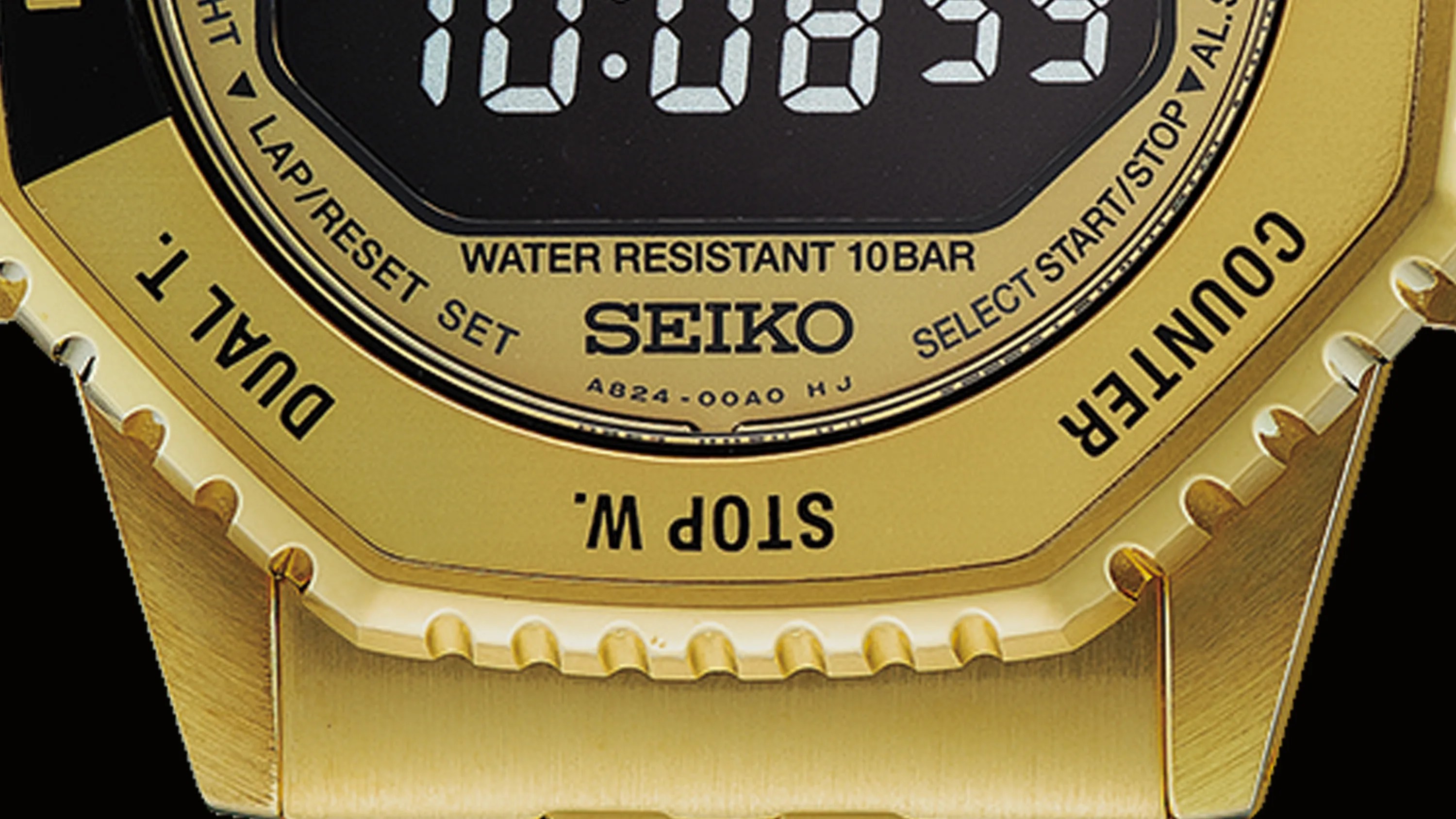Close-up of a gold Seiko digital watch face showing water resistance, buttons, and part of the metal band.