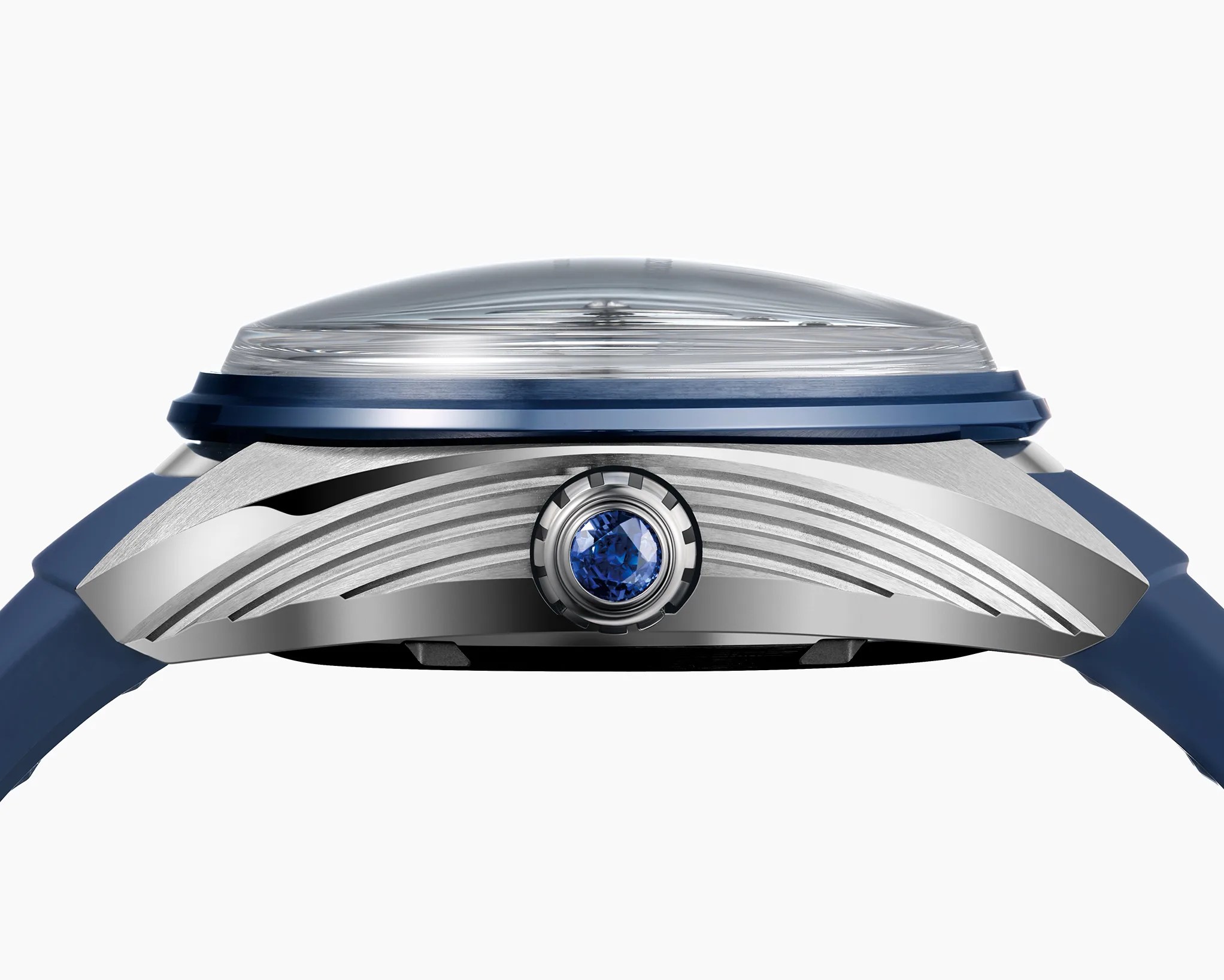 Side view of a silver watch case with a blue crown featuring a blue gemstone and a domed crystal on top.