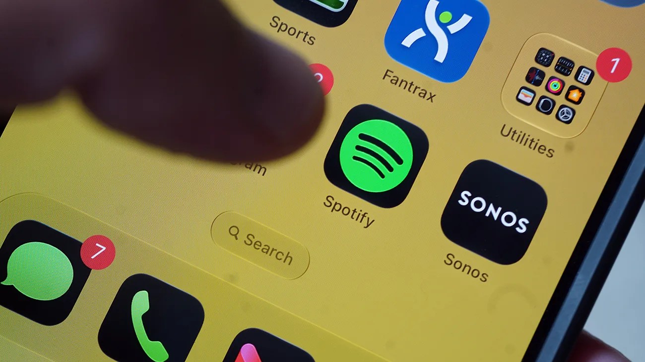 Close-up of a smartphone screen showing app icons including Spotify, Sonos, Messages with 7 notifications, and Utilities with 1 notification.