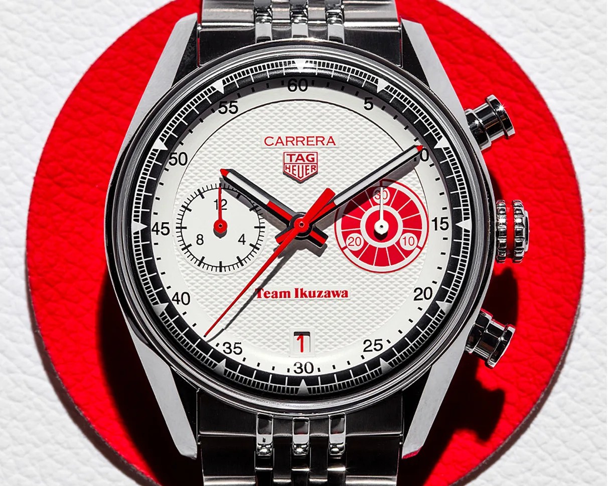 TAG Heuer Carrera wristwatch with white textured dial, red and black accents, and stainless steel bracelet on a red and white background.