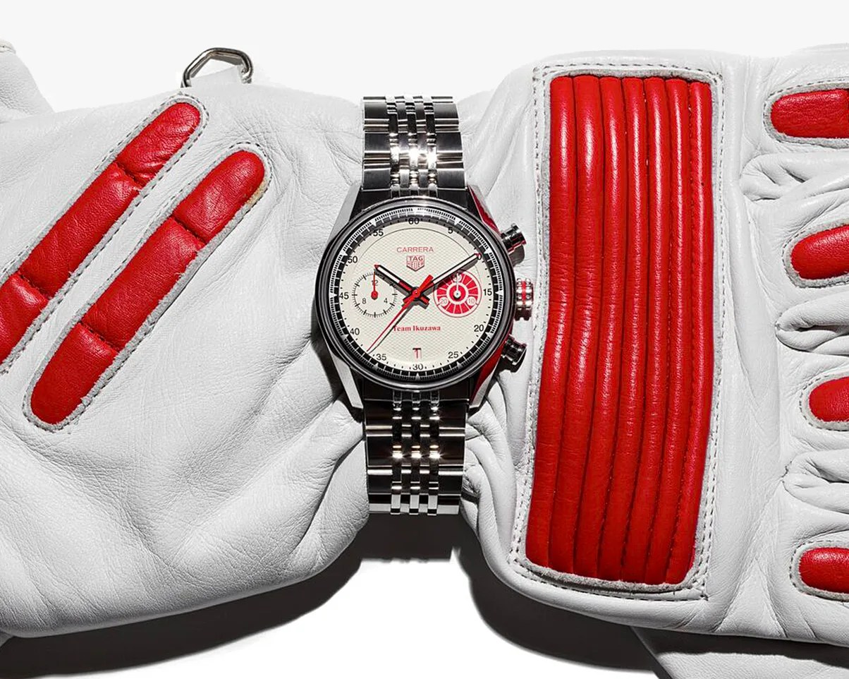 Silver TAG Heuer Carrera wristwatch with white and red dial on white leather gloves with red padded accents.