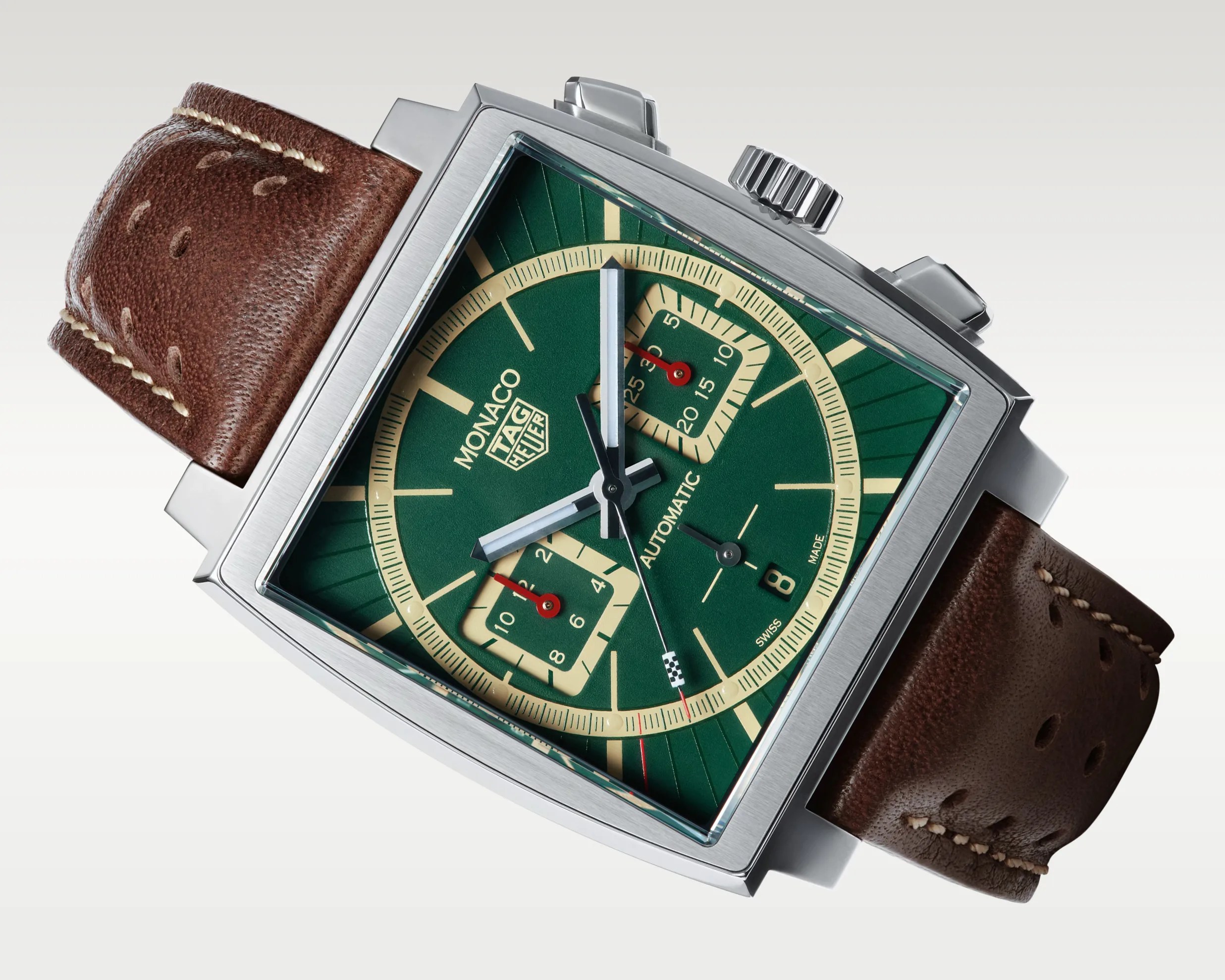 Square stainless steel TAG Heuer Monaco watch with green dial, beige accents, and brown perforated leather strap.