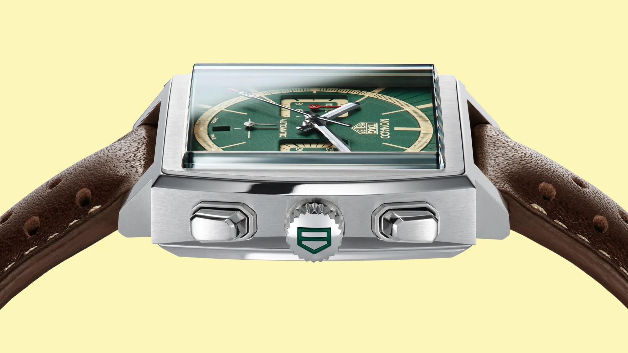 Square stainless steel TAG Heuer Monaco watch with green dial and brown perforated leather strap.