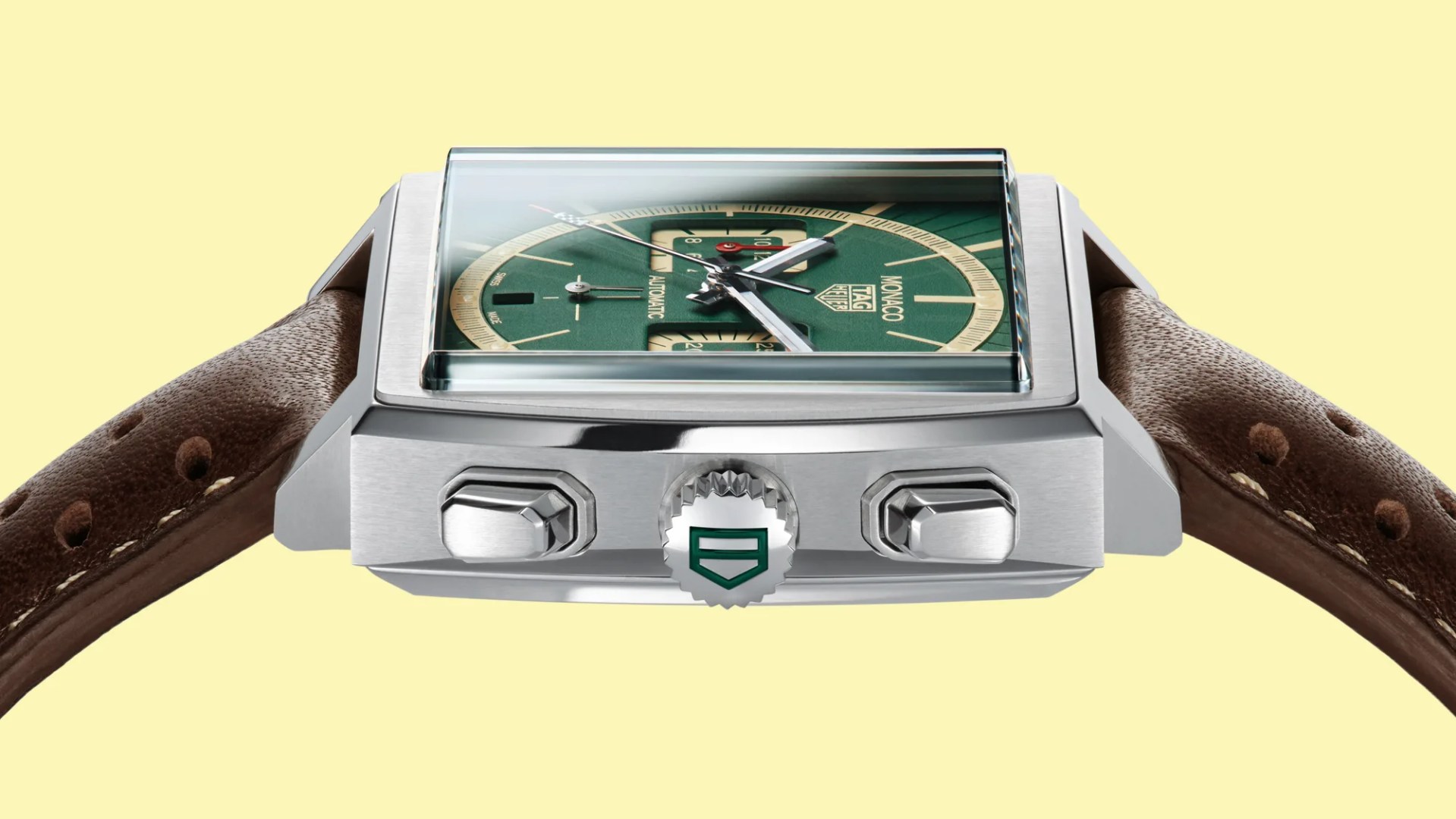 Square stainless steel TAG Heuer Monaco watch with green dial and brown perforated leather strap.