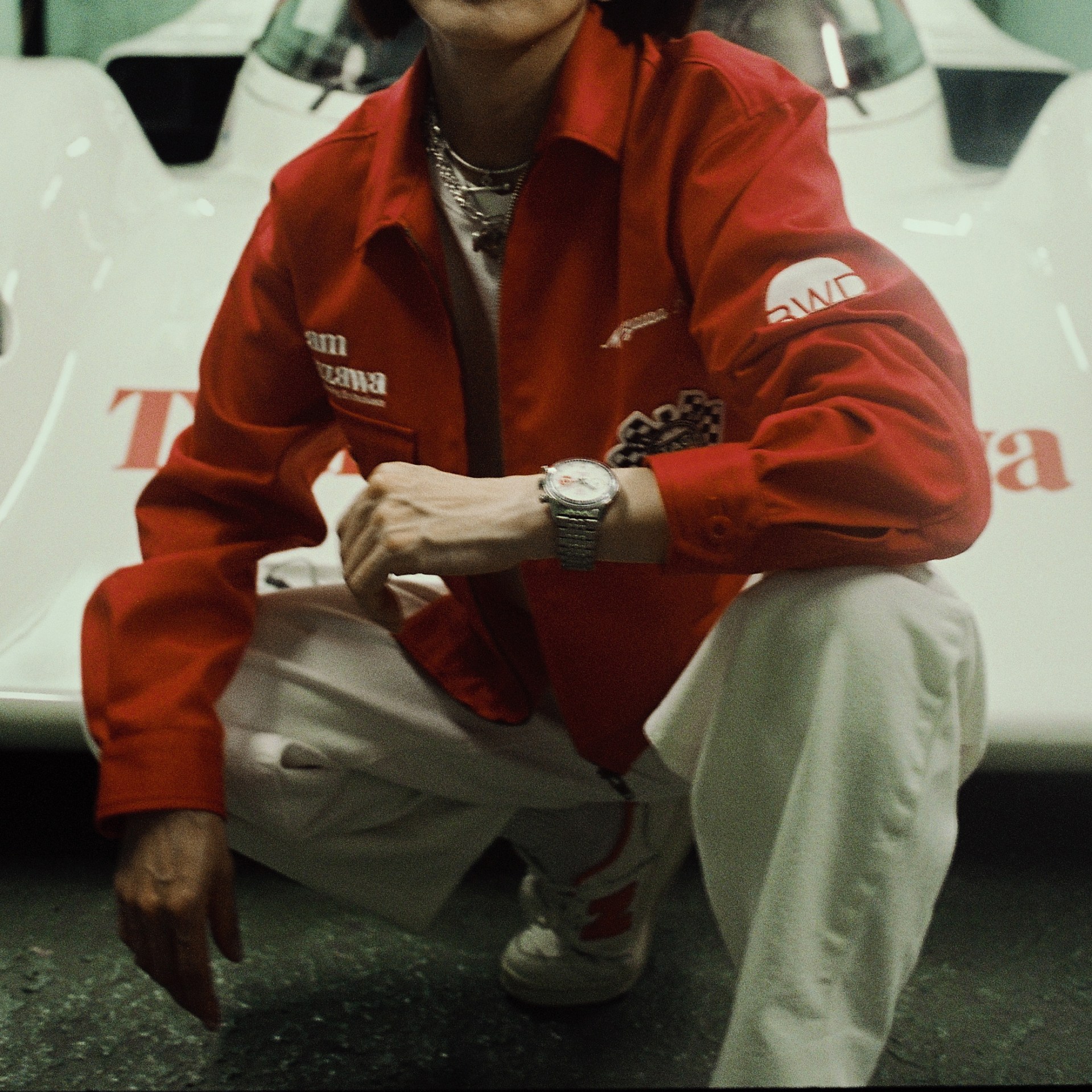 Kırmızı Team Ikuzawa TAG Heuer ceketi giyen kişi ve yarış aracı
