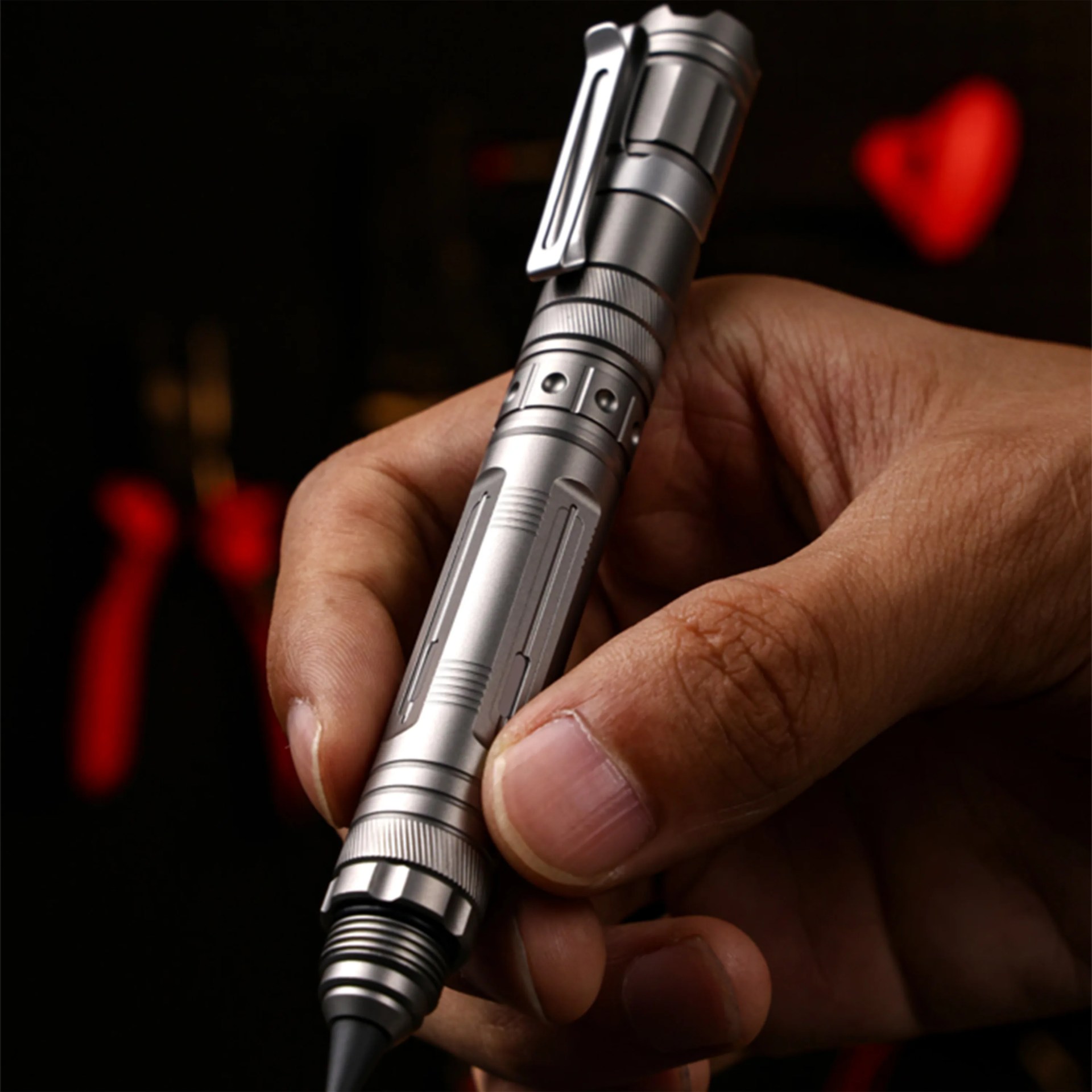 Close-up of a hand holding a silver metal pen with a clip and a black tip.