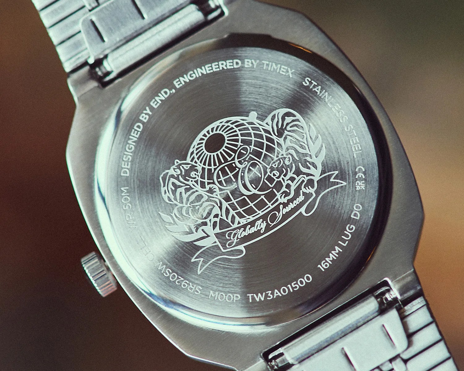 Back of a stainless steel Timex watch with engraved globe, tigers, and text "Globally Sourced.