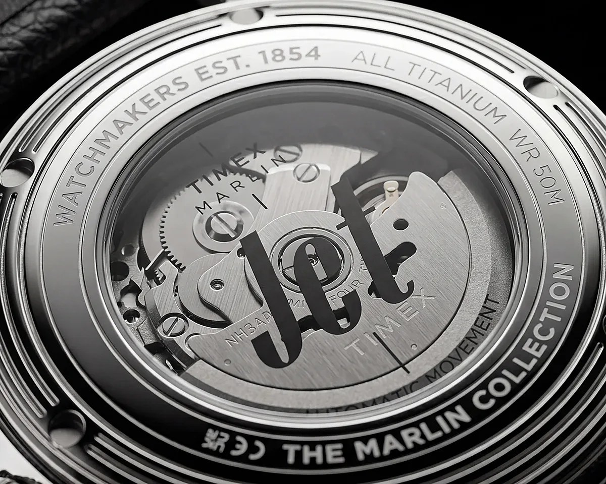 Close-up of the back of a Timex Marlin automatic watch with visible mechanical movement and engraved text on a titanium case.