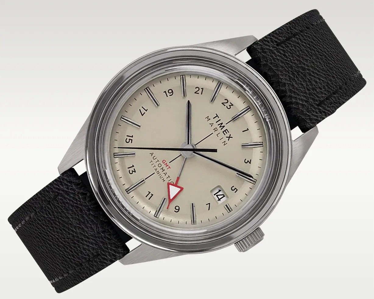 Timex Marlin automatic titanium watch with beige dial, black leather strap, and red GMT hand.
