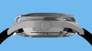 Side view of a silver metal watch case with a domed crystal and black leather strap against a blue background.