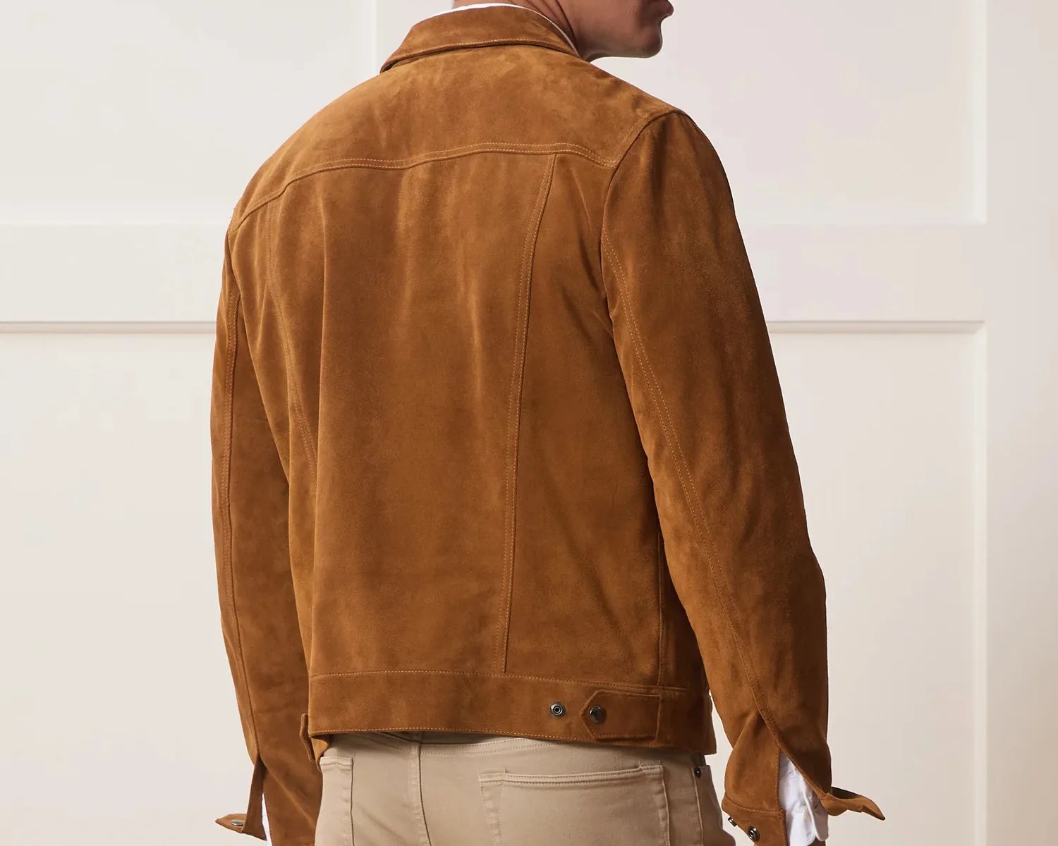 Brown suede jacket with buttoned adjustable waist tabs worn by a person facing away.