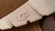 Close-up of a beige textured shoe sole with the embossed "GG" logo on a brown fabric and leather background.
