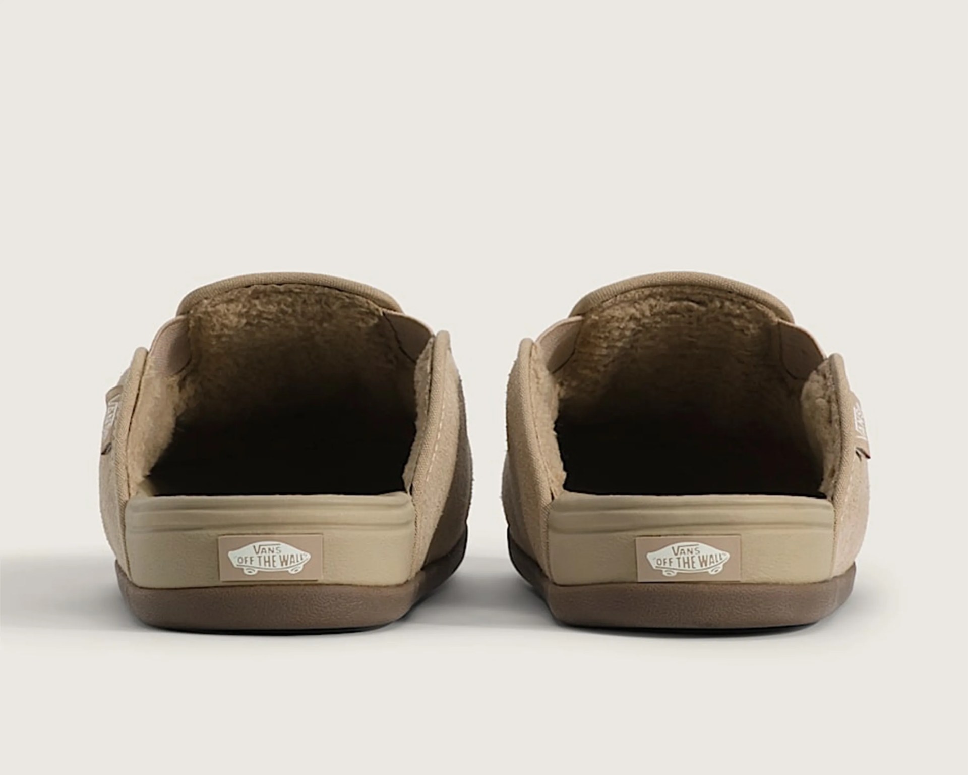 Pair of beige Vans slip-on shoes with "Off The Wall" logo on the heel, viewed from the back.