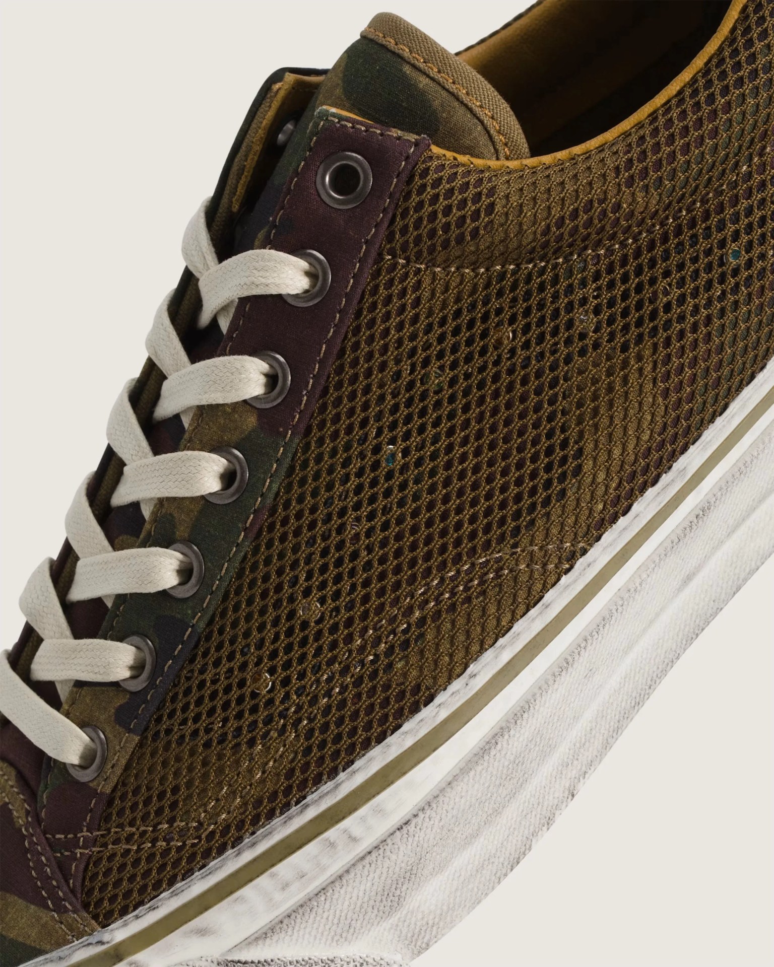 Close-up of a brown mesh sneaker with white laces and a white rubber sole.