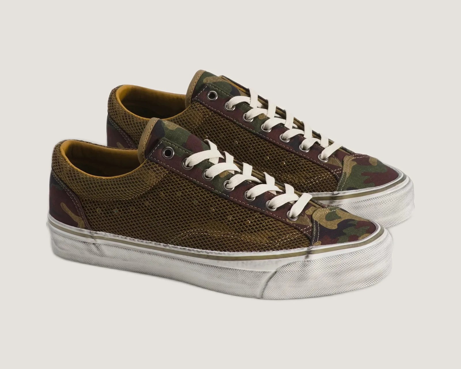 Pair of low-top sneakers with white laces, camouflage fabric, and brown mesh panels on white rubber soles.