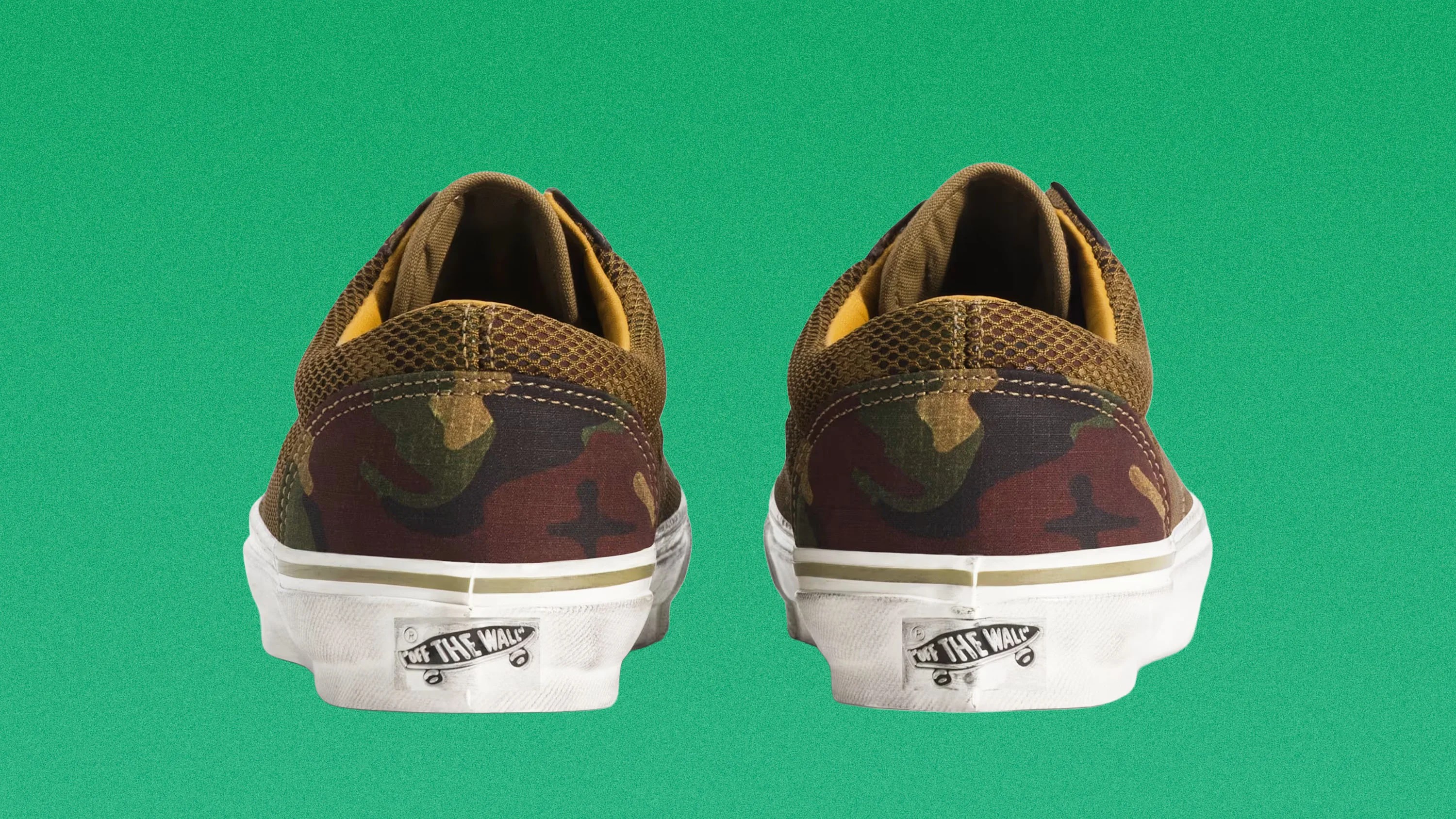 Pair of brown and green camouflage Vans sneakers shown from the back on a green background.