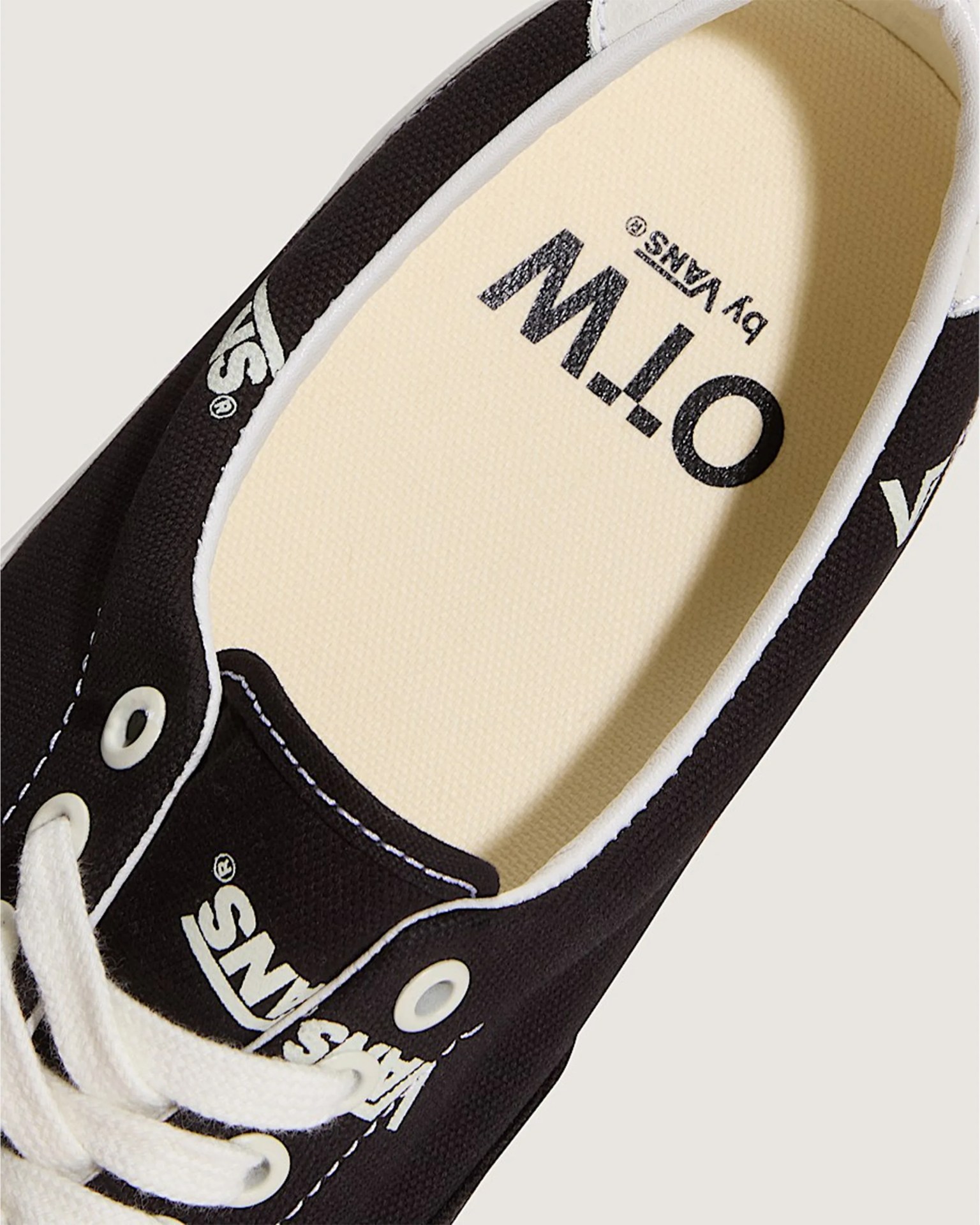 Black Vans sneaker with white laces and O.T.W by Vans printed on the beige insole.