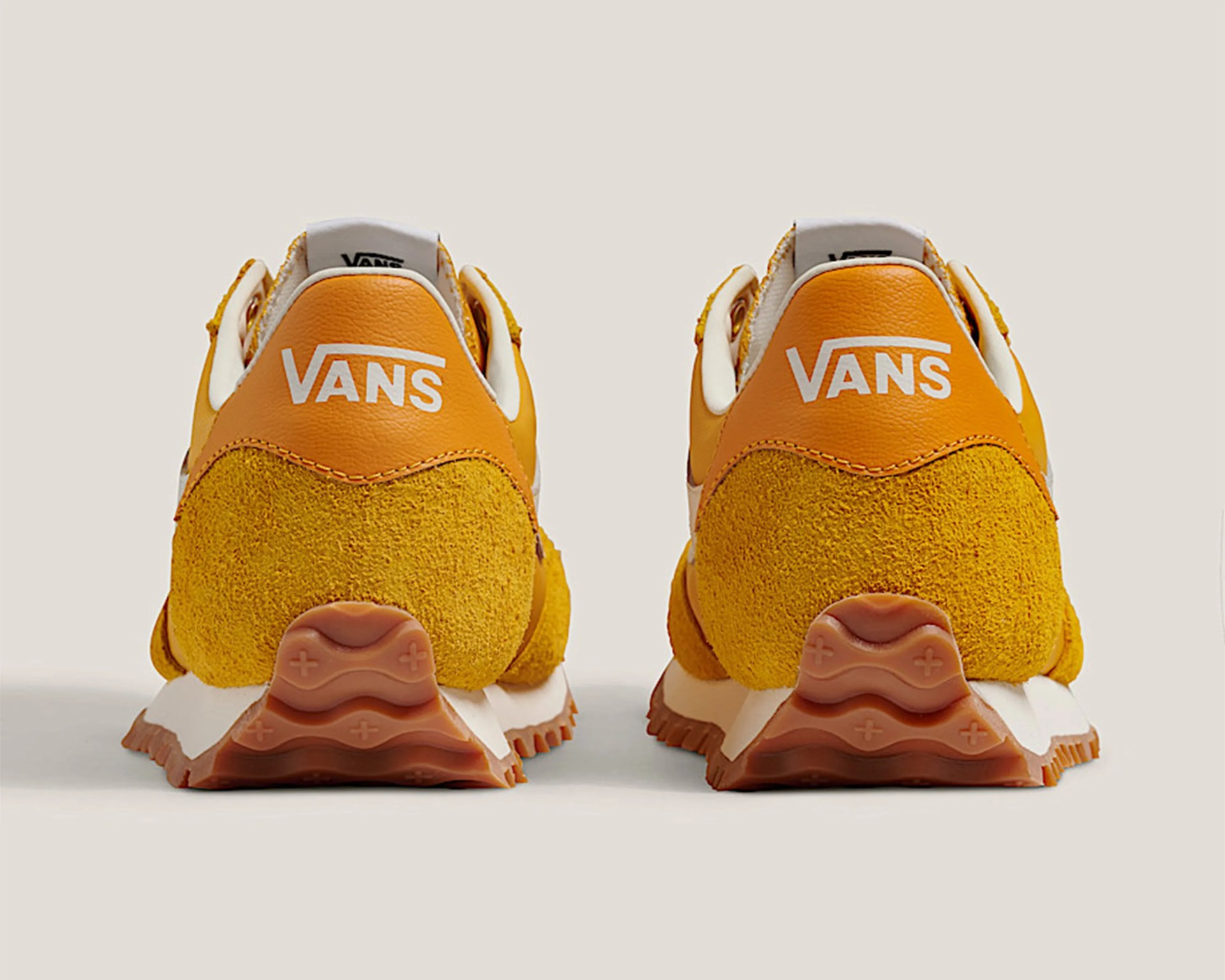 Pair of yellow Vans sneakers with white Vans logo on the heel and brown rubber soles.