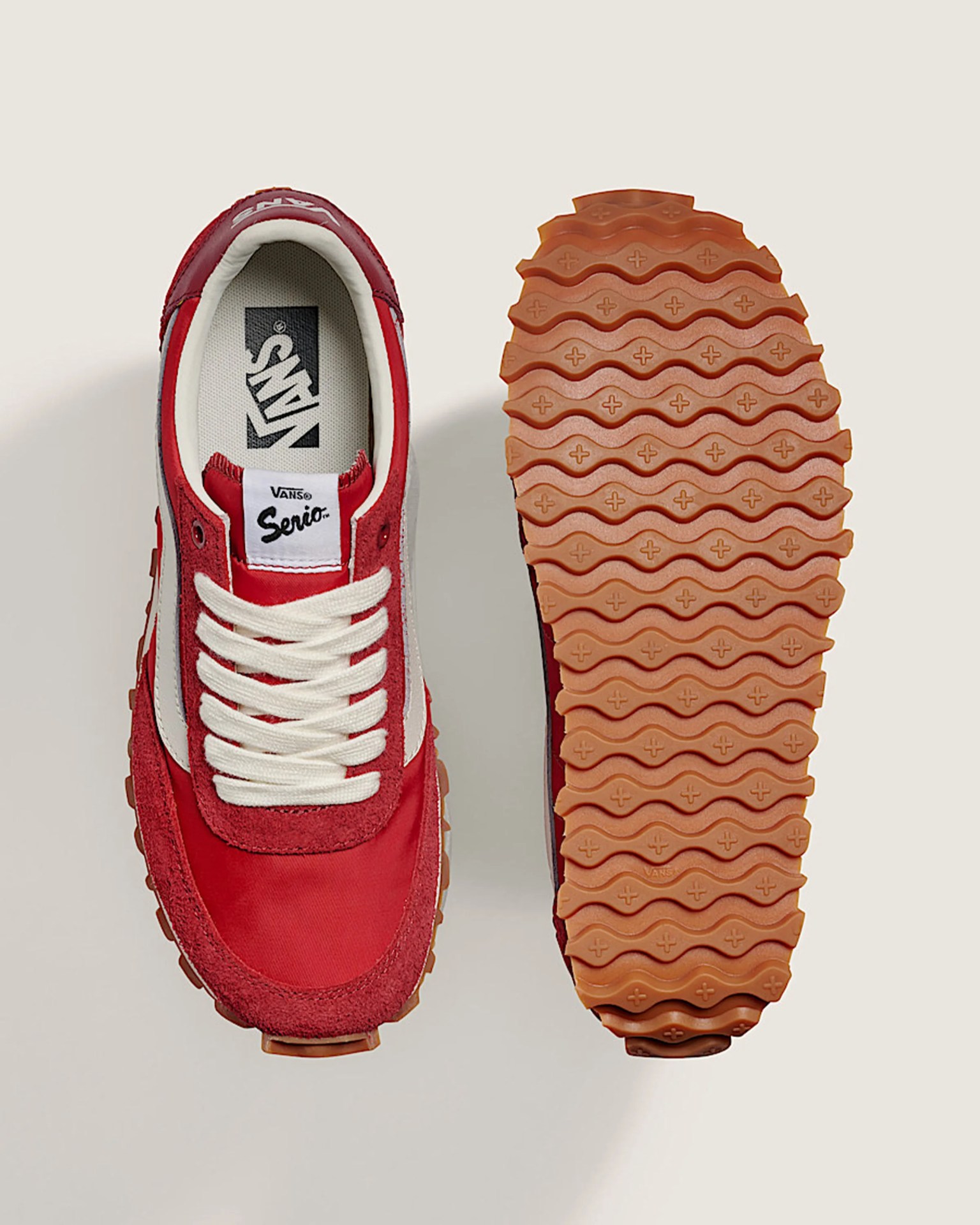 Red and white Vans sneaker with white laces and a gum sole showing tread pattern.