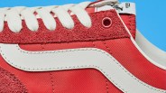 Close-up of a red sneaker with white laces and a white leather stripe on the side against a blue background.