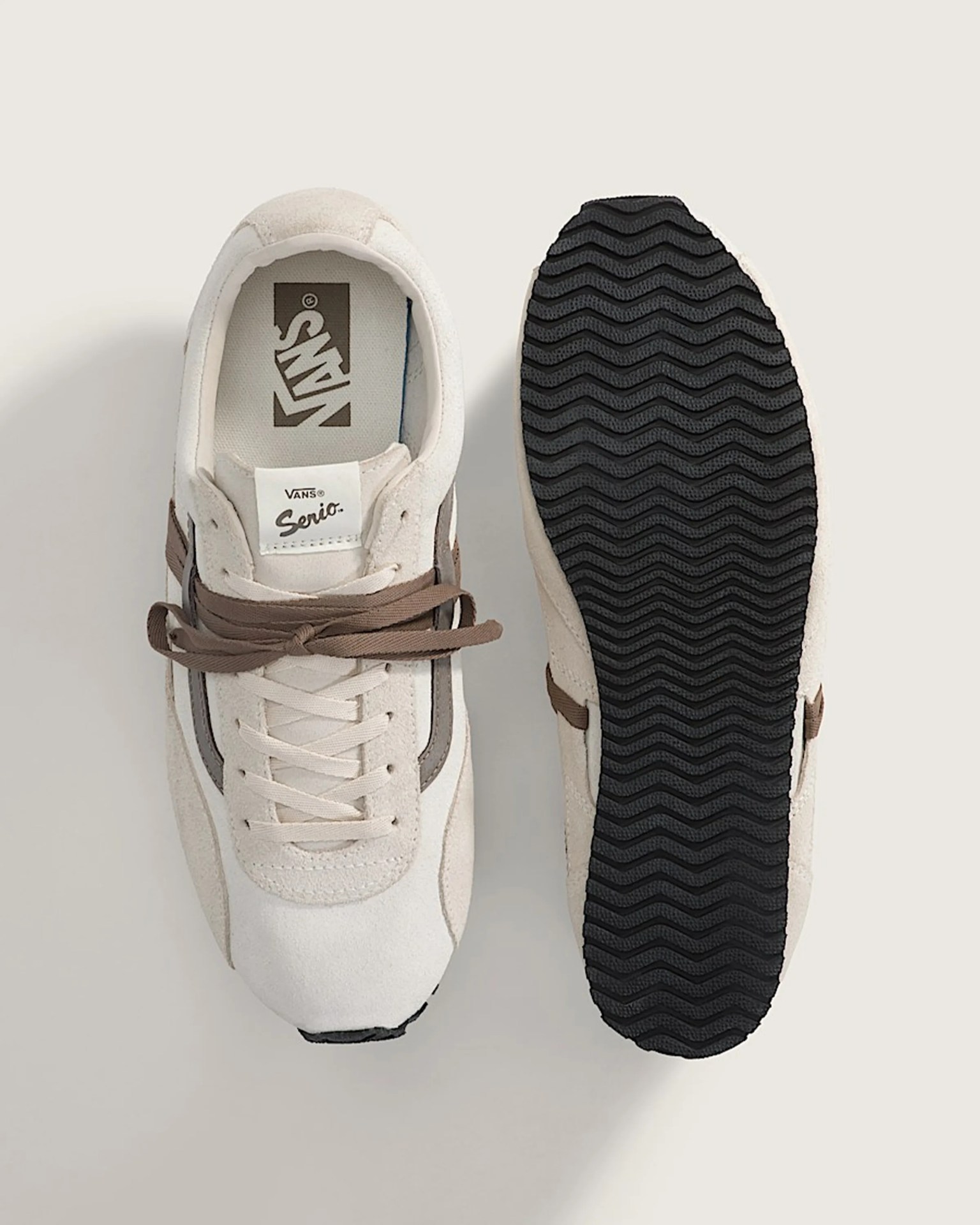 Pair of beige Vans Serio sneakers with brown laces, one showing top view and the other sole with black zigzag tread.