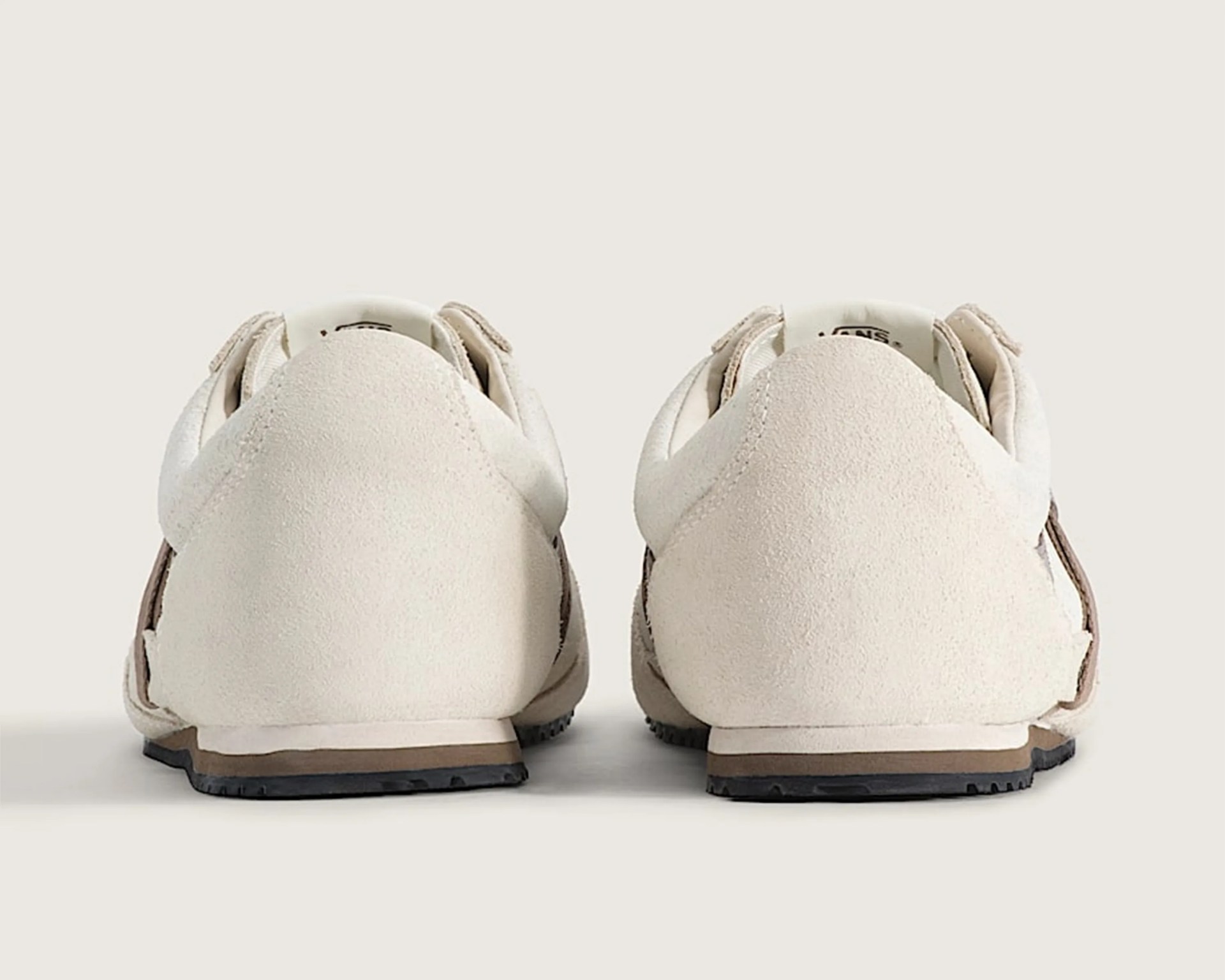 Pair of beige suede sneakers shown from the back with black rubber soles.