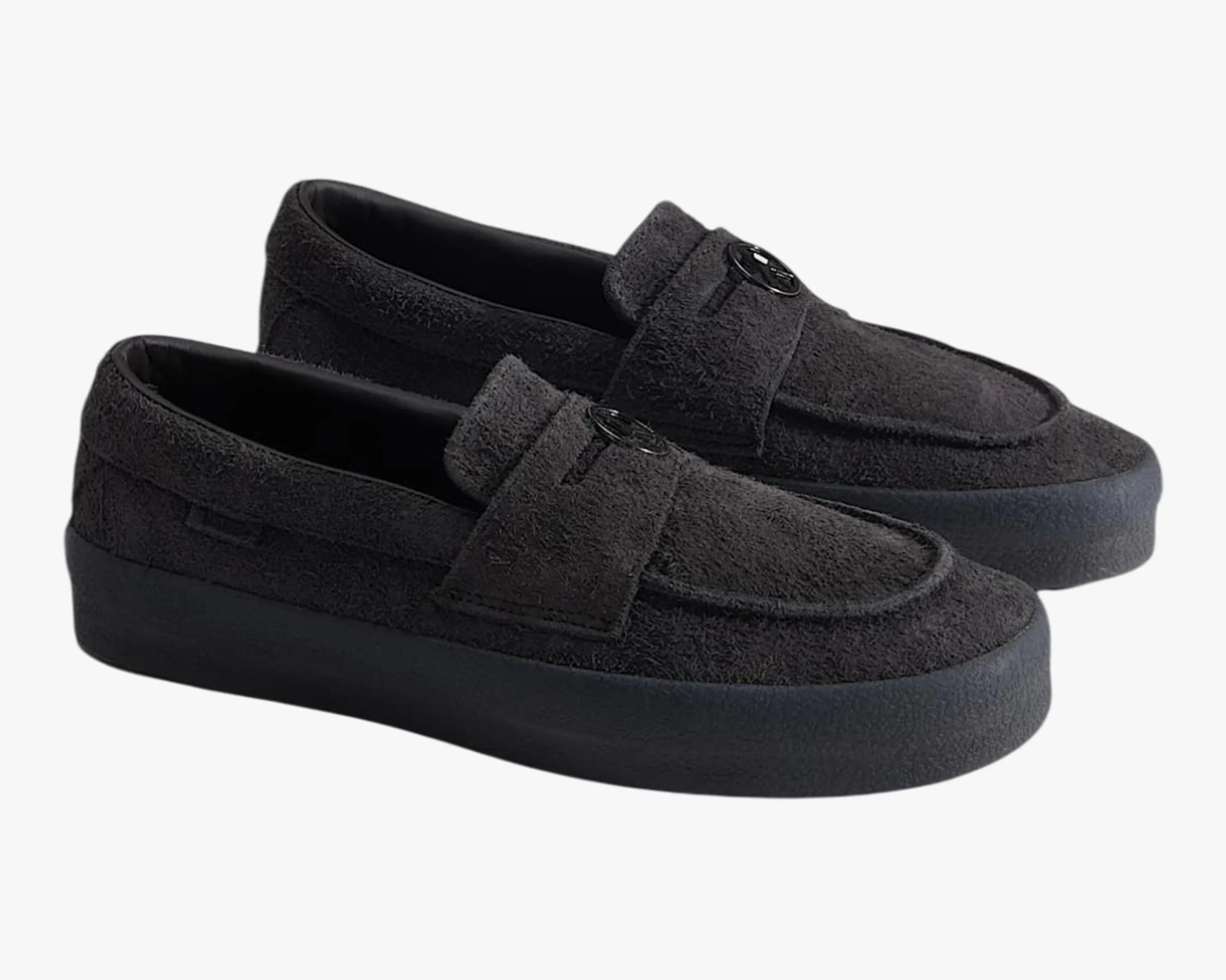Pair of black suede loafers with black rubber soles and a round black emblem on the strap.