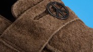 Close-up of a brown textured fabric with a black circular peace symbol attached.