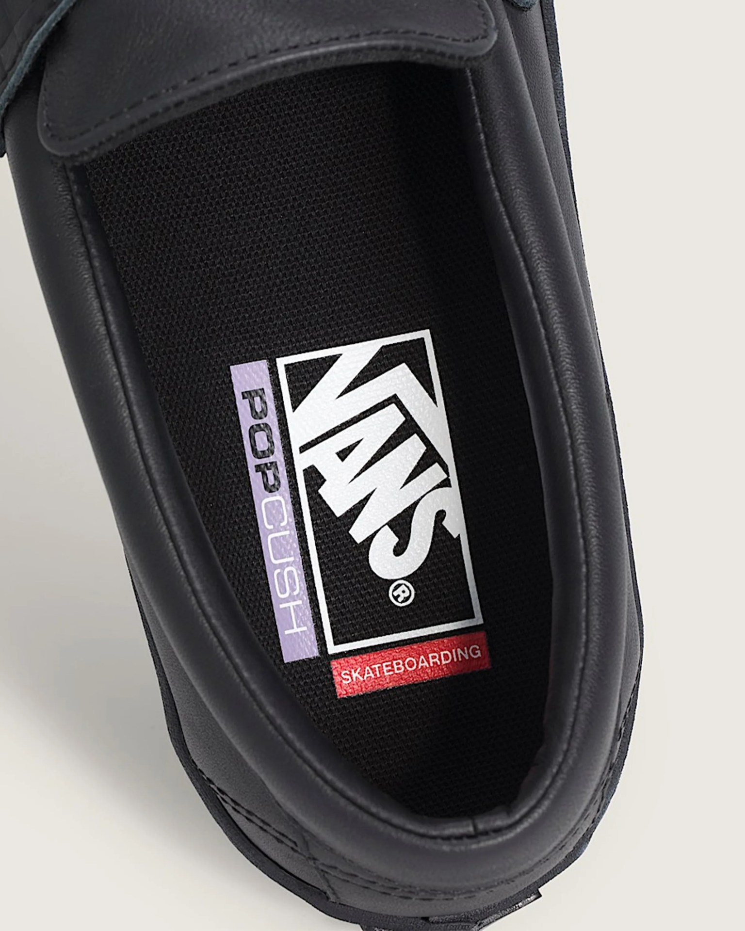 Close-up of black Vans shoe interior showing "POP CUSH" and "SKATEBOARDING" text on the insole.