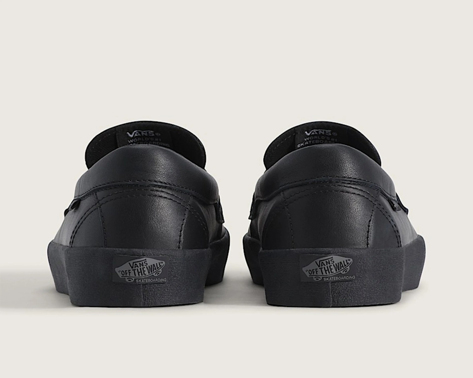 Pair of black Vans leather sneakers shown from the back with "Off The Wall" logo on the sole.
