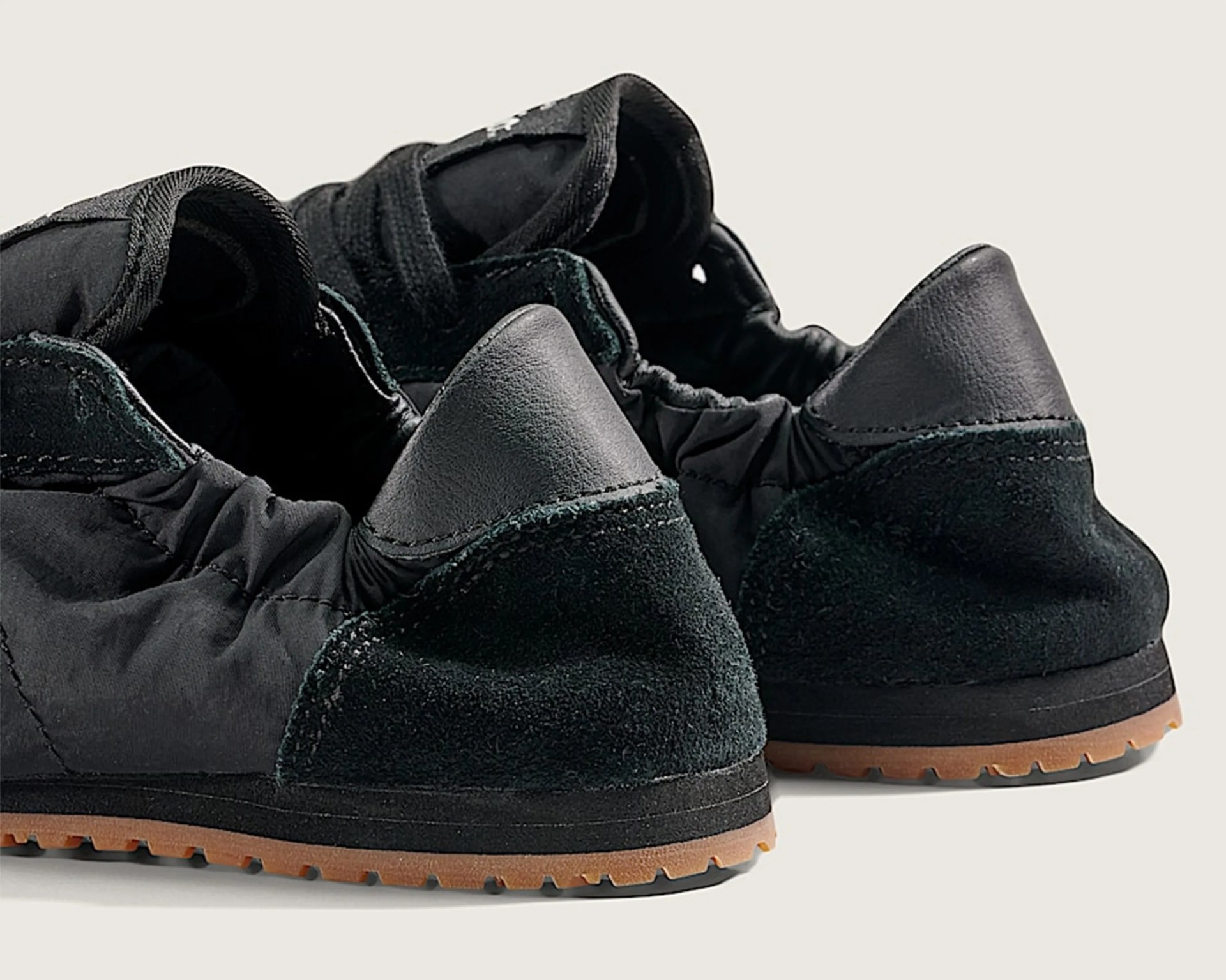 Pair of black sneakers with suede and leather heel accents and gum rubber soles.