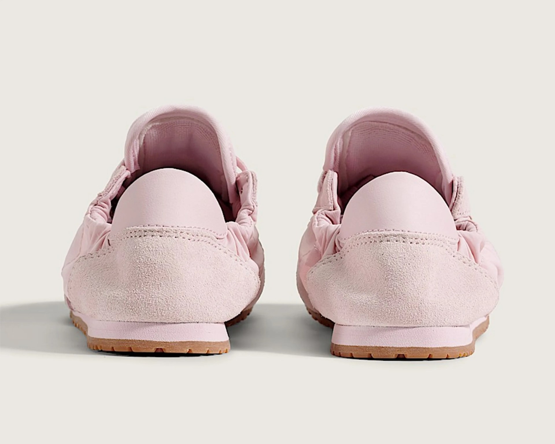 Pair of light pink suede sneakers viewed from the back on a light background.