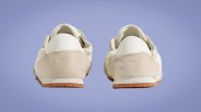 Pair of off-white sneakers with beige suede heel patches and gum rubber soles viewed from the back.