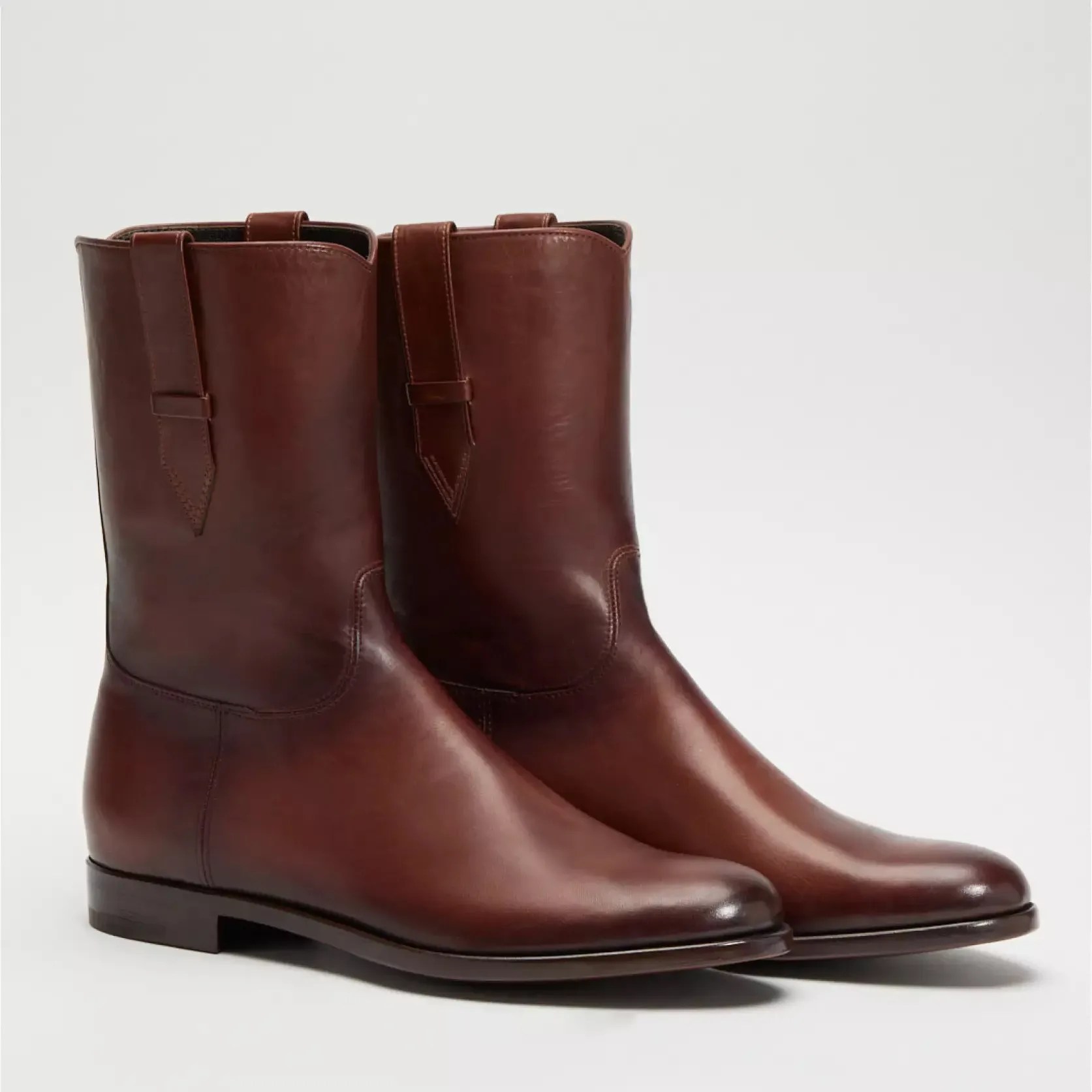 Pair of mid-calf brown leather boots with pull tabs and low stacked heels on a white background.