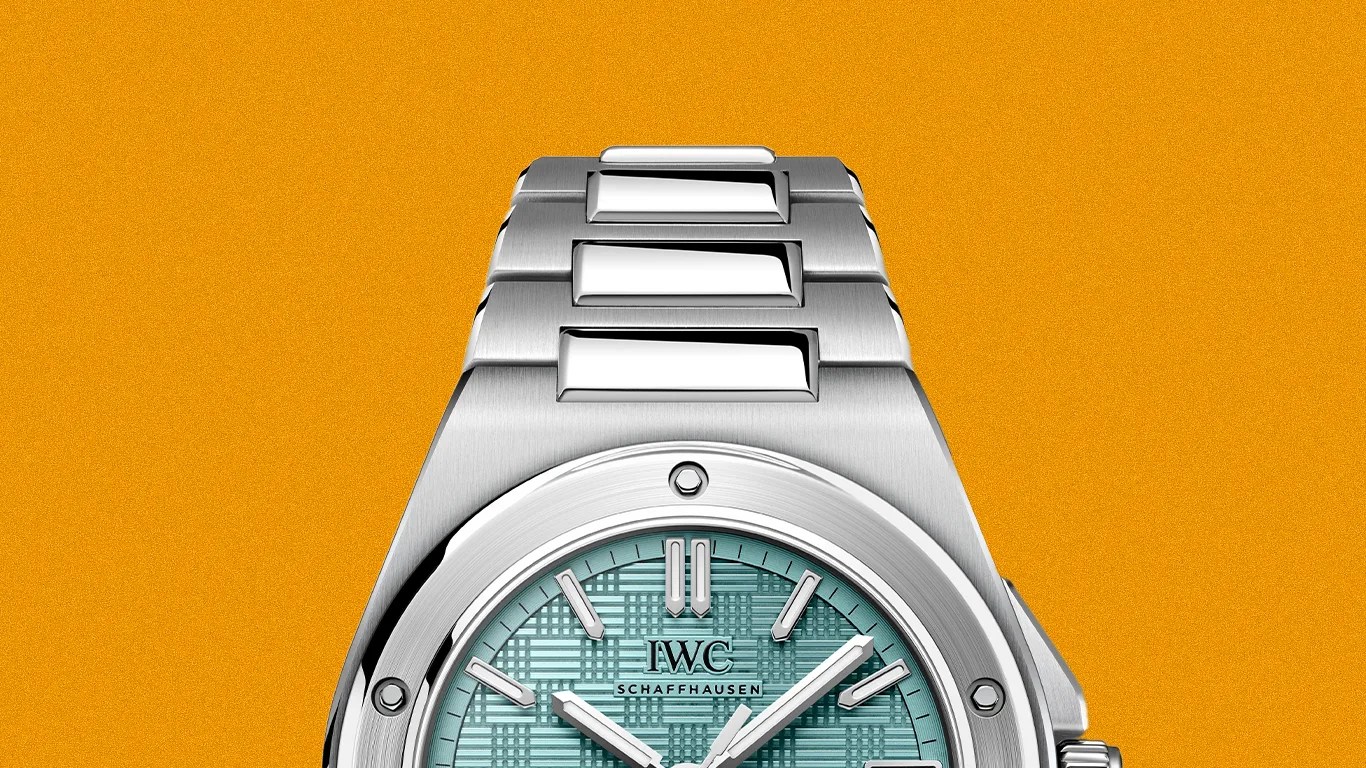 Stainless steel IWC Schaffhausen wristwatch with a textured turquoise dial and silver hour markers on an orange background.