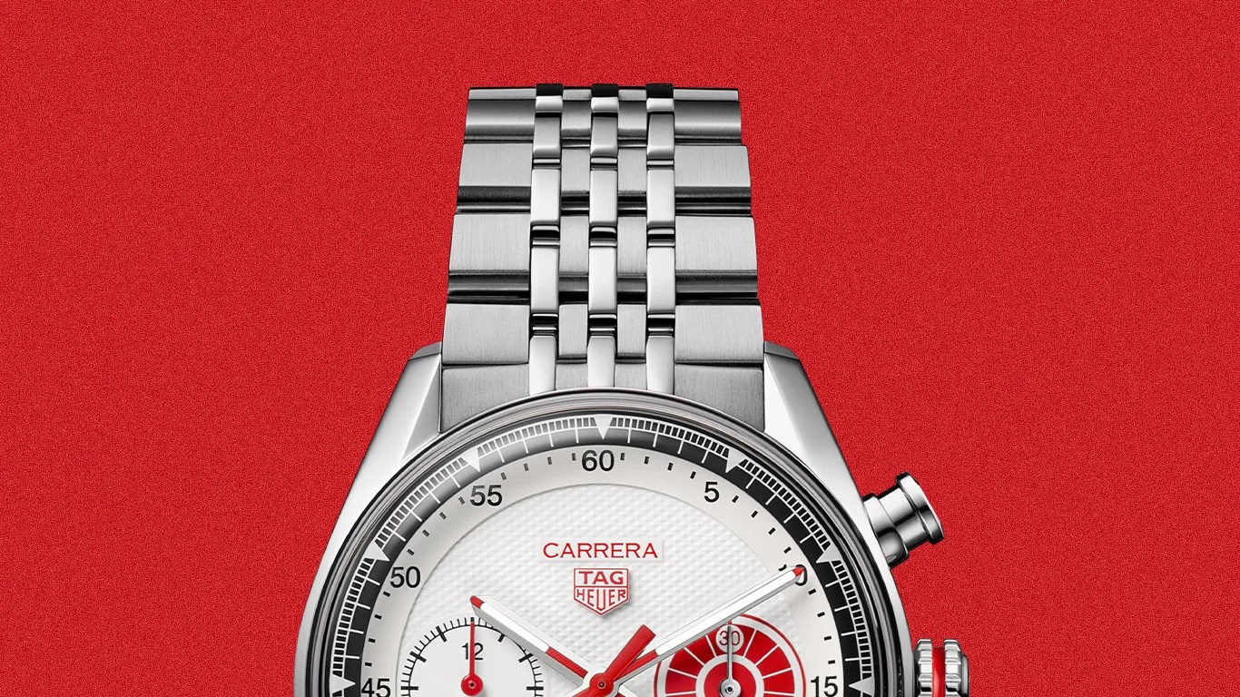 Silver TAG Heuer Carrera watch with white dial, red accents, and stainless steel bracelet on a red background.