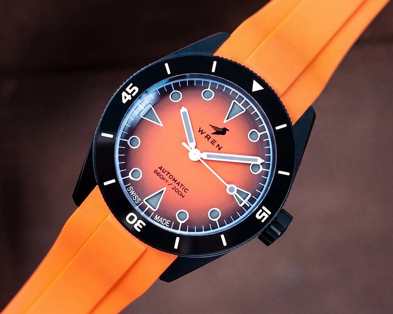 Black-cased wristwatch with orange gradient dial, white markers, and orange rubber strap.