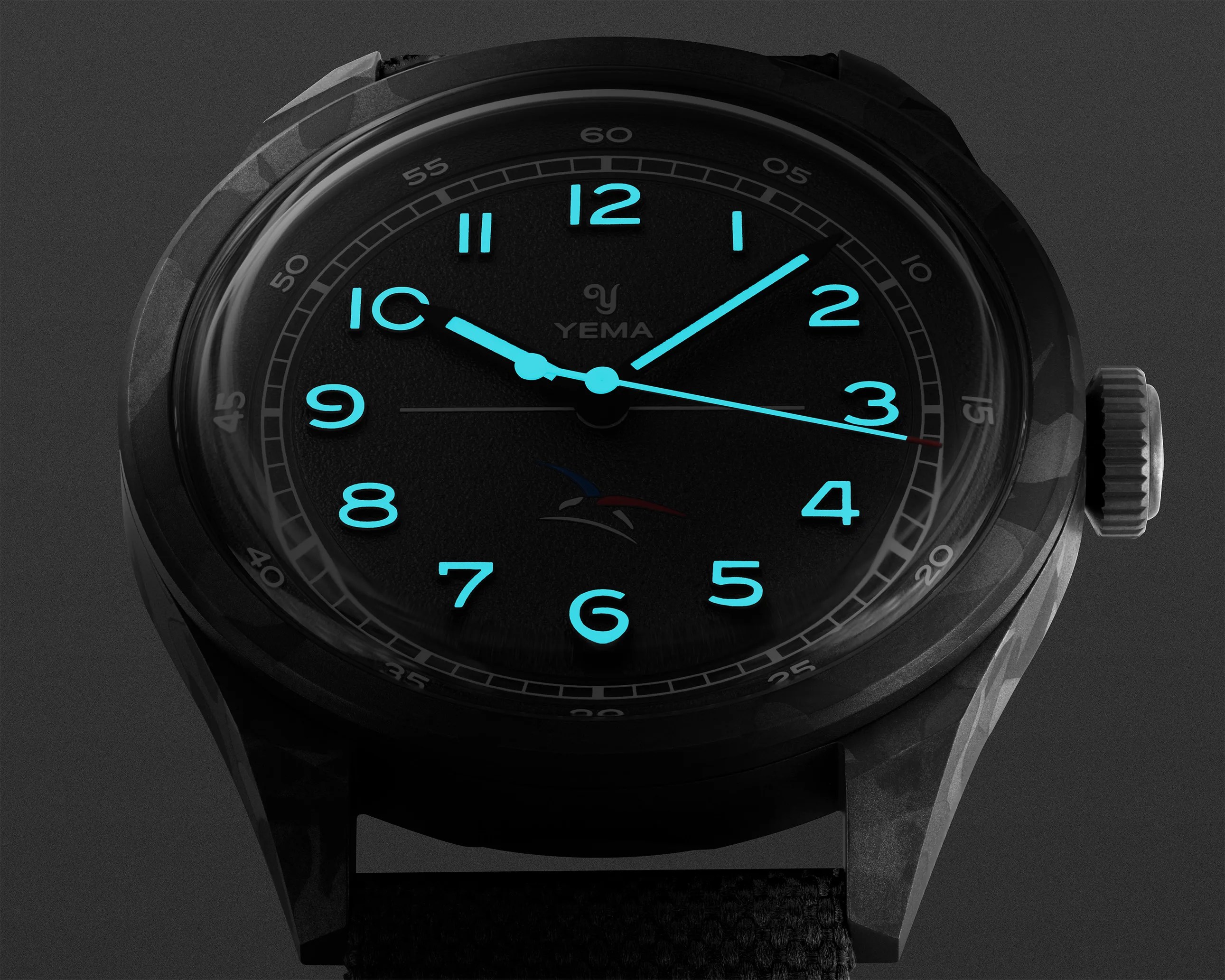 Black Yema wristwatch with glowing blue Arabic numerals and hands on a dark textured dial.