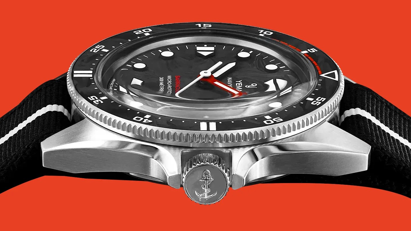 Close-up of a Yema Navygraf Barracuda dive watch with a black bezel, black dial, and black fabric strap with white stripes.