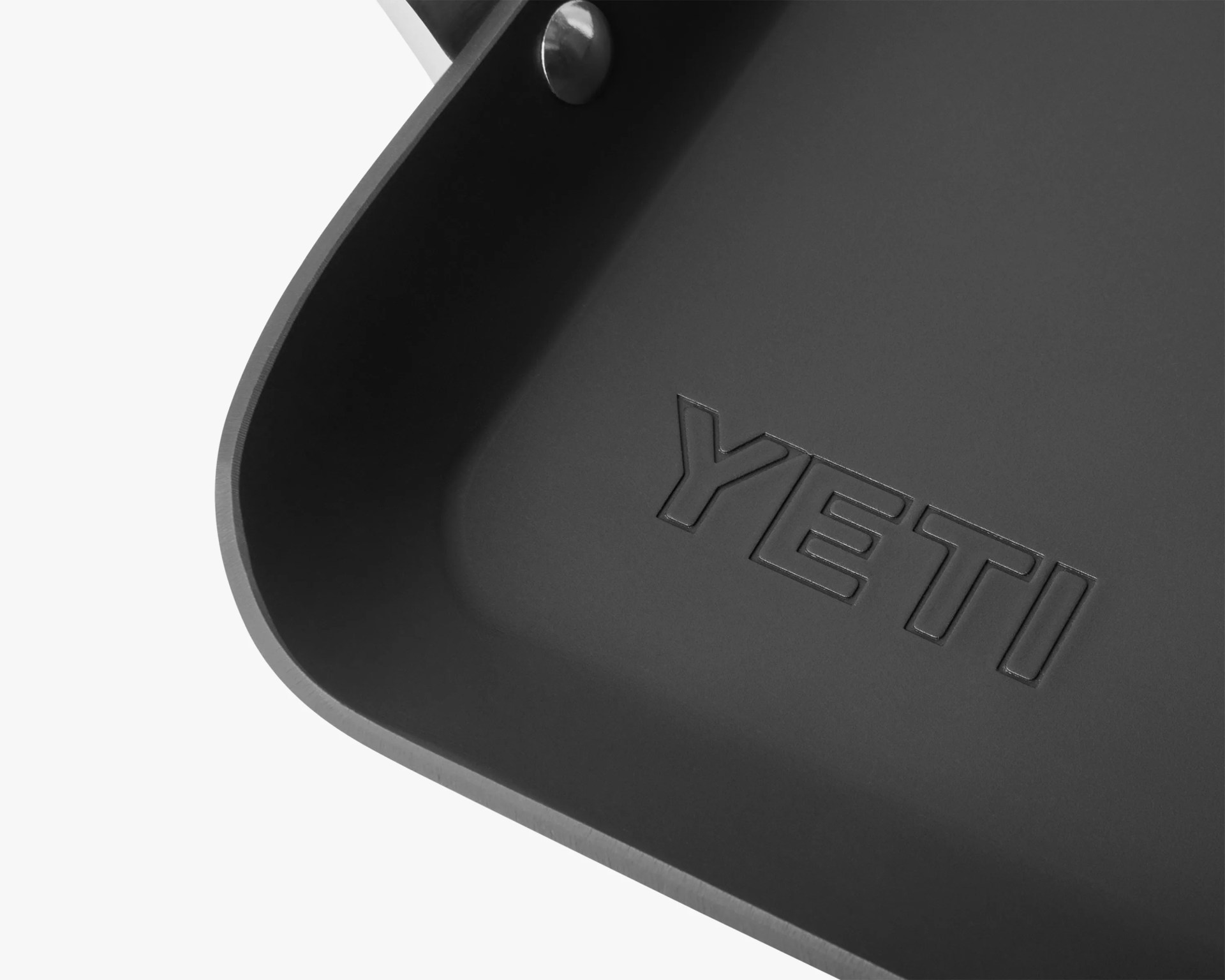 Close-up of a black YETI branded container corner with a metal rivet on a white background.