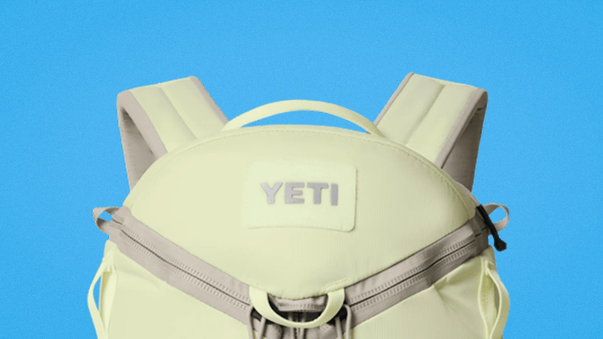 Light yellow YETI backpack with padded shoulder straps and front zipper pocket against blue background.