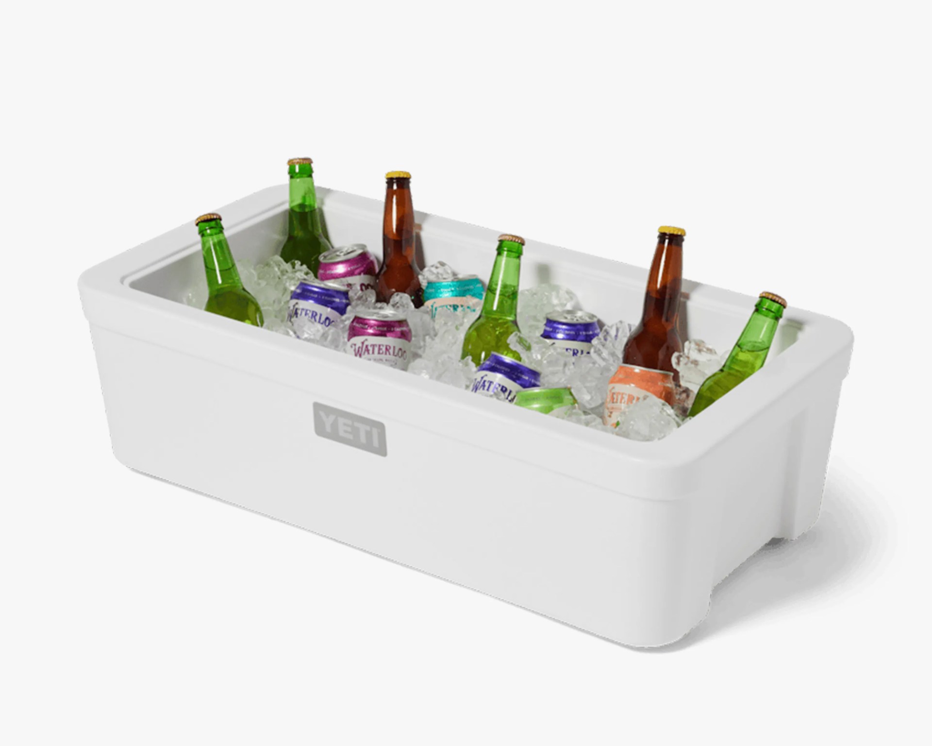 White YETI cooler filled with ice, green and brown glass bottles, and colorful cans.