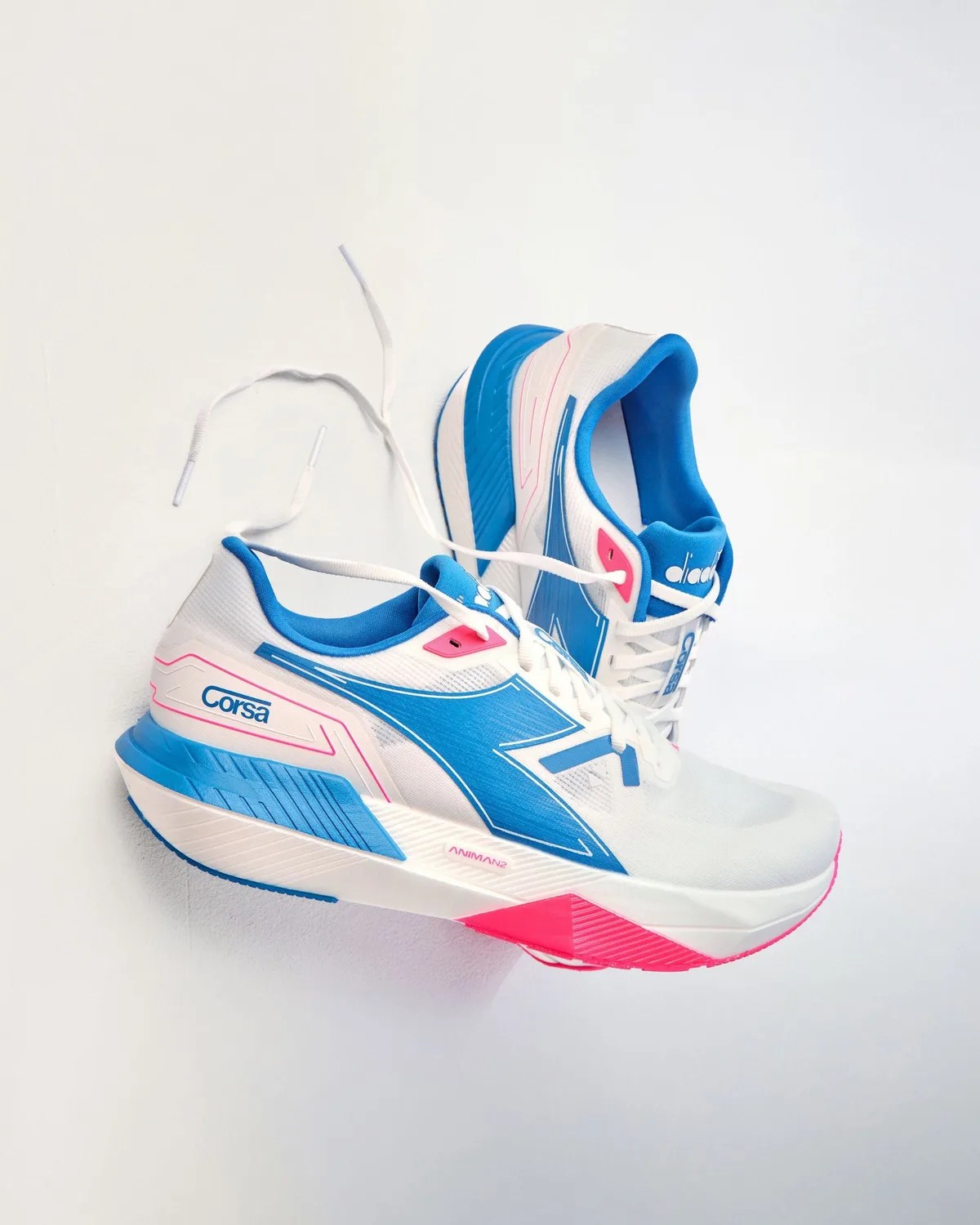 Pair of white running shoes with blue and pink accents and white laces on a white background.