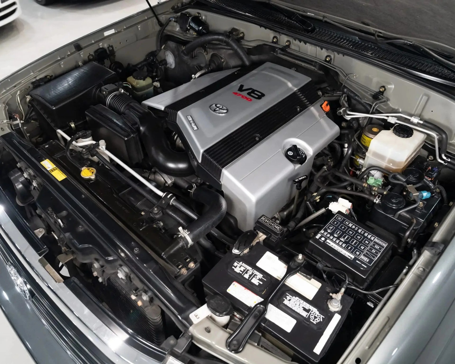 Toyota V8 4.7L engine with silver and black cover inside a car engine bay.
