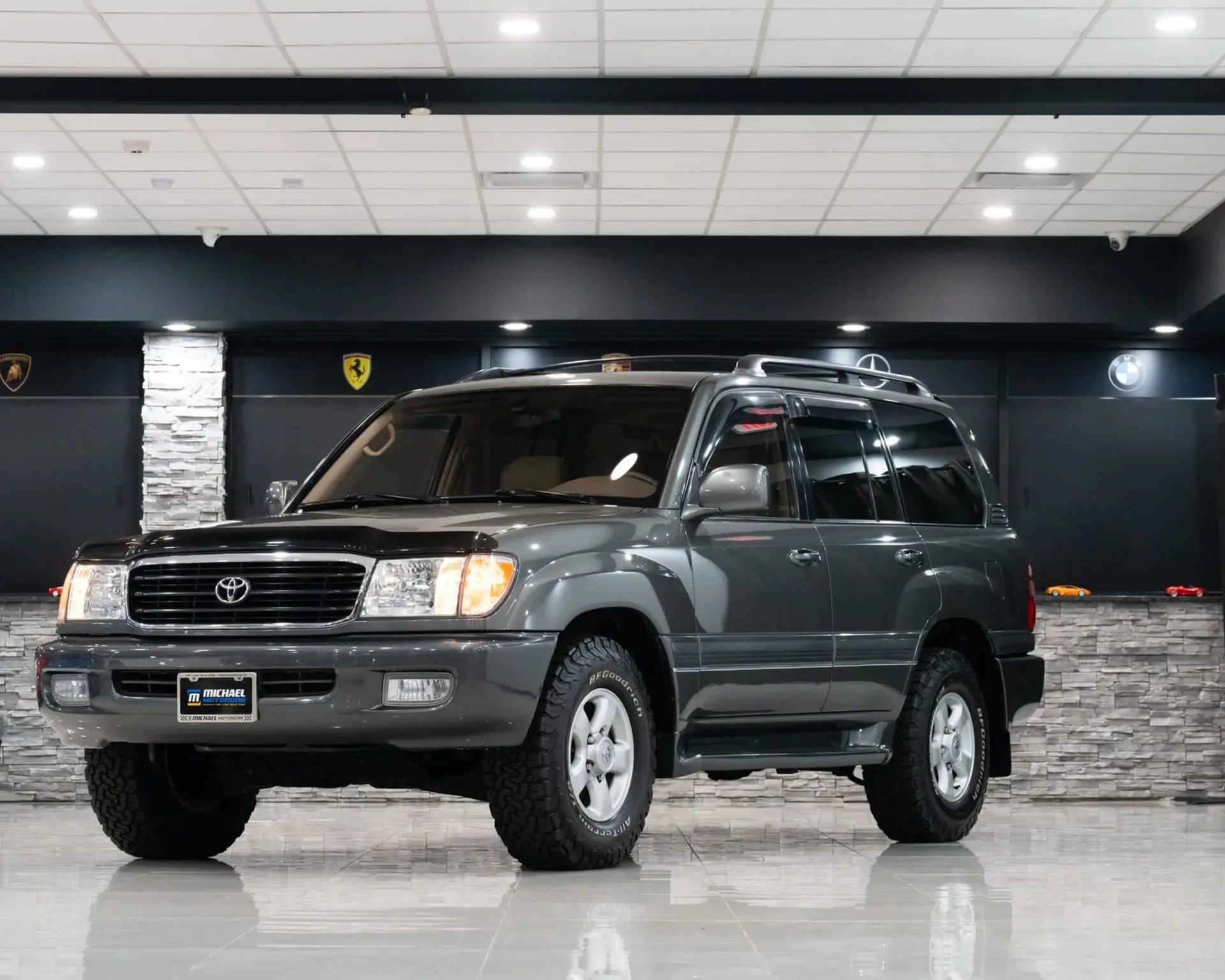 Gray Toyota SUV with off-road tires parked indoors on a shiny tiled floor.