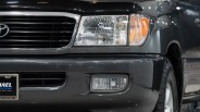 Front right side of a dark gray Toyota SUV showing the headlight, grille, and fog light.