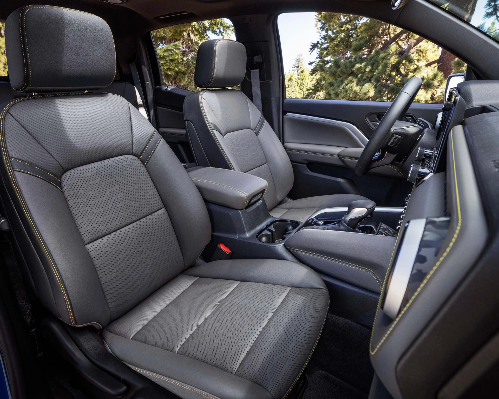 Gray leather car seats with yellow stitching inside a vehicle cabin.