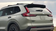 Rear side view of a light green Honda CR-V Hybrid SUV with roof rails and black trim.