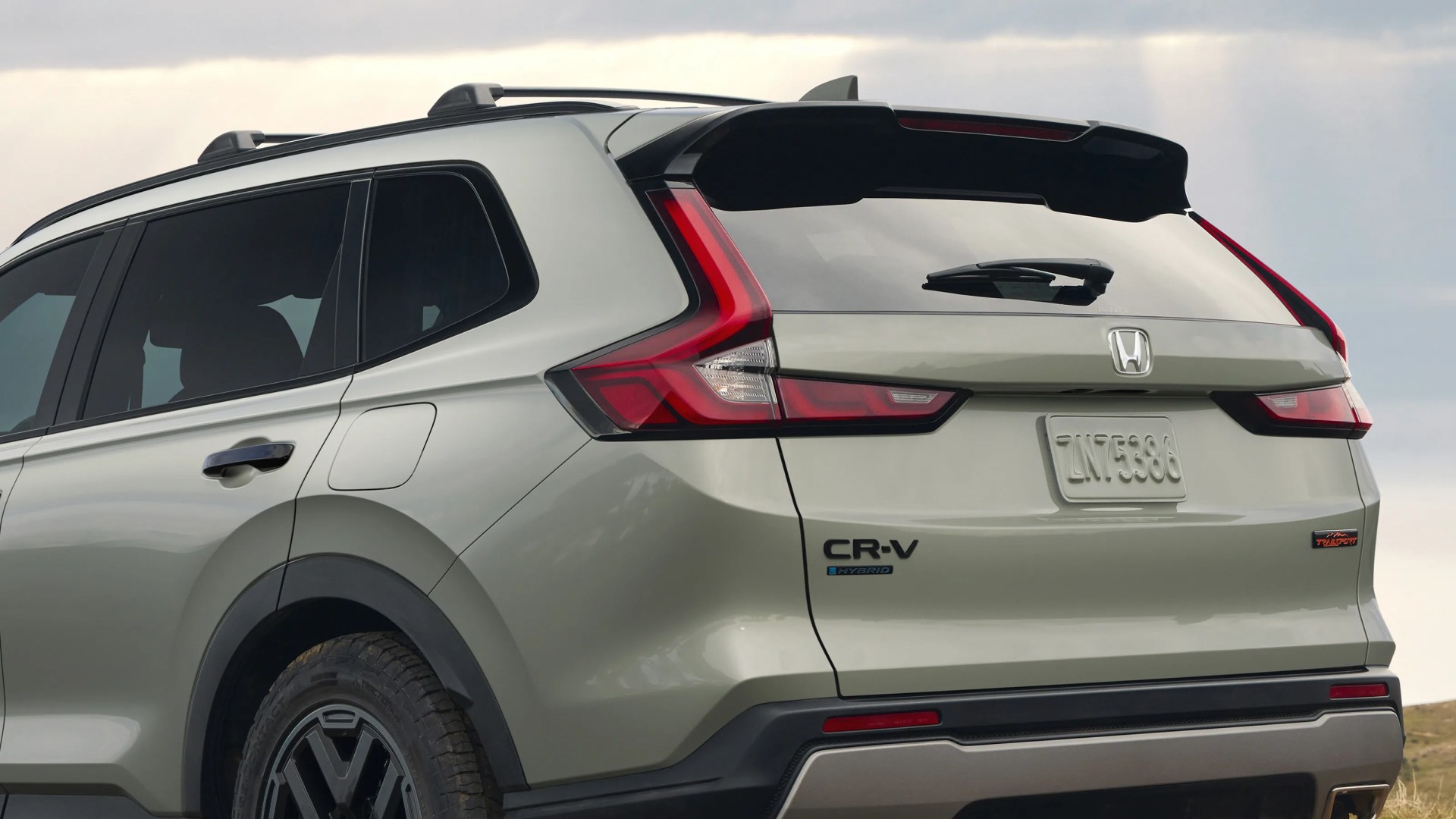 Rear side view of a light green Honda CR-V Hybrid SUV with roof rails and black trim.